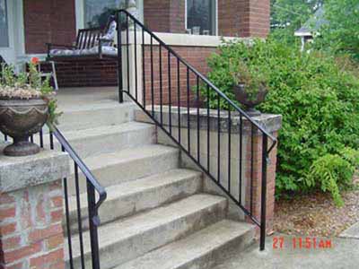 Metal stair rail inside existing concrete porch wing wall